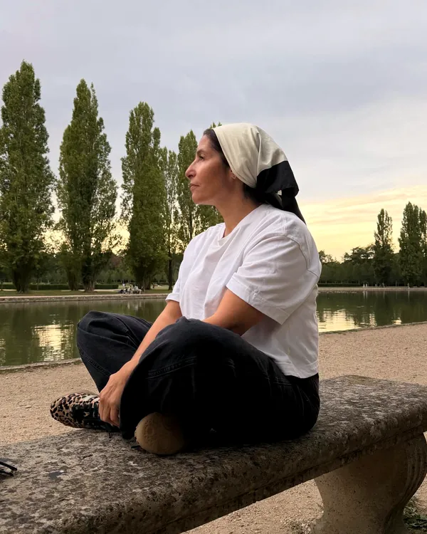 Zora Khadraoui, kinésiologue, assise en tailleur sur un banc au bord d'un bassin